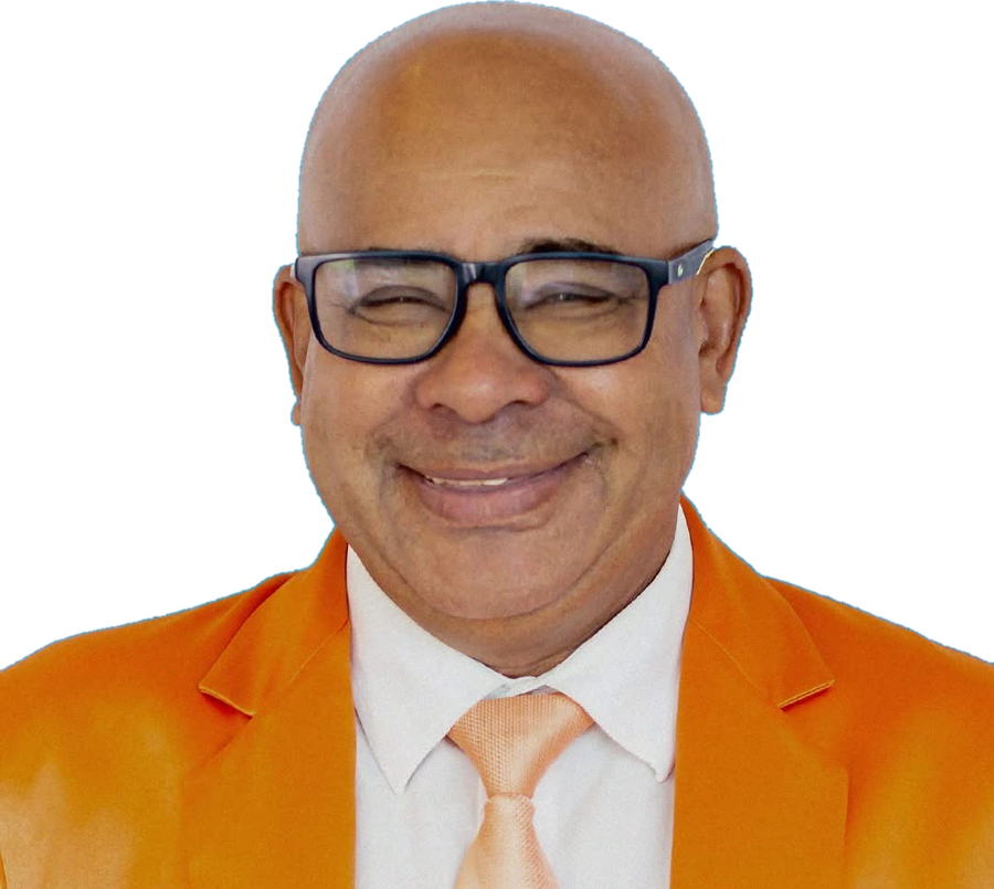 Romério Duarte, de terno laranja, camisa branca e óculos, sorrindo.